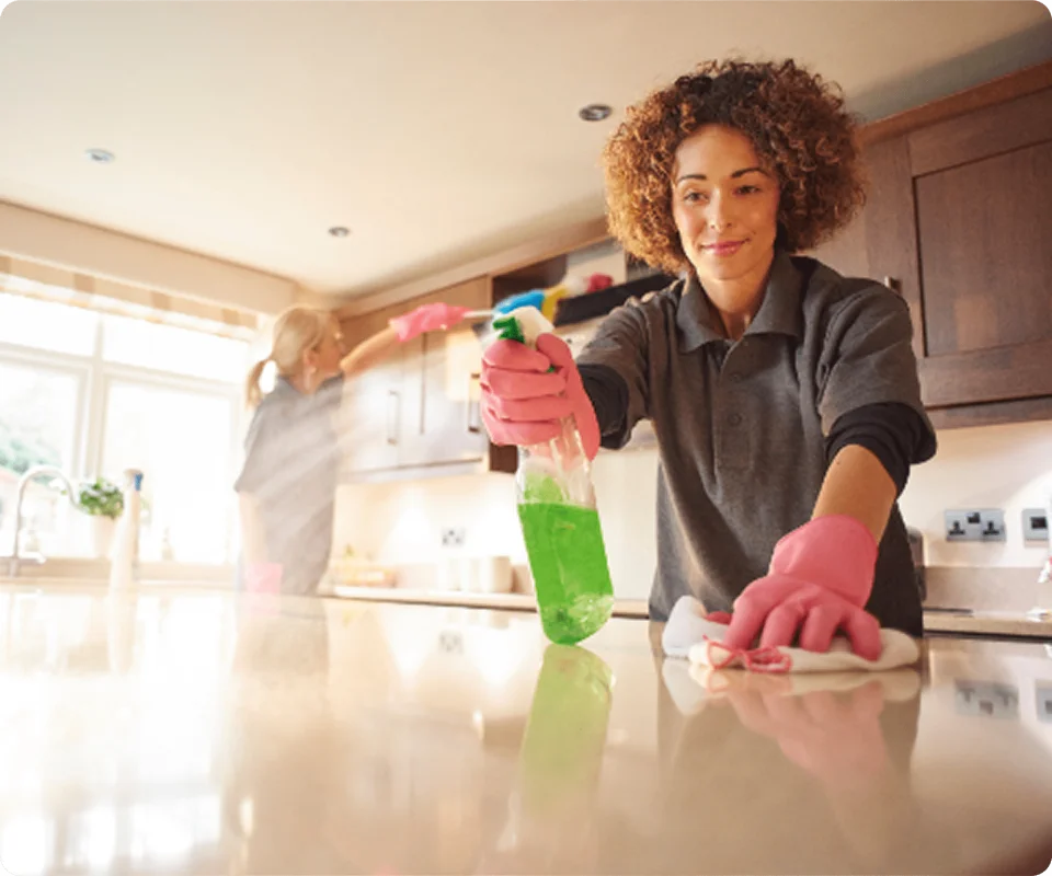 Professional cleaner wiping and sanitizing a kitchen countertop.