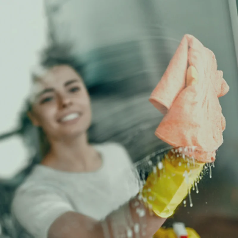 Smiling cleaner washing a window with a microfiber cloth.